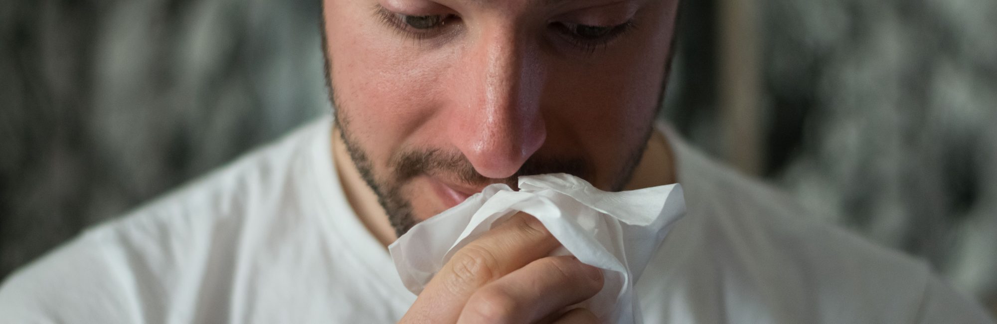 Man wiping his nose on a tissue Avoid Colds Flu And Covid If You Are Living In A Shared House