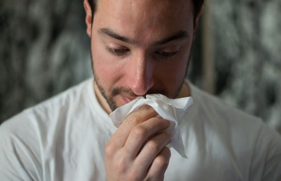 Man wiping his nose on a tissue Avoid Colds Flu And Covid If You Are Living In A Shared House